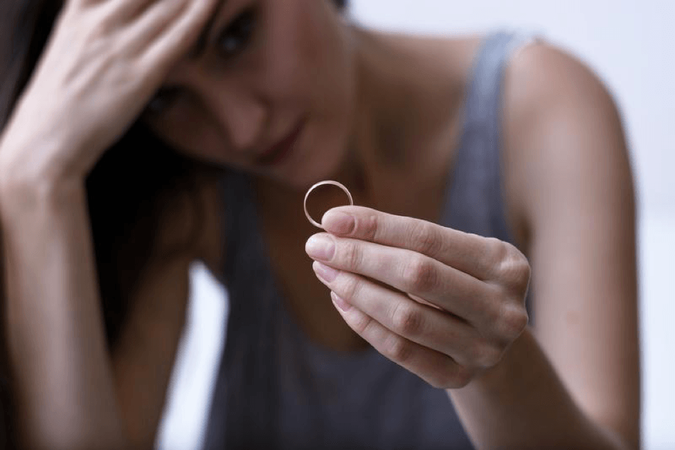 A woman is holding a wedding ring in her hand.